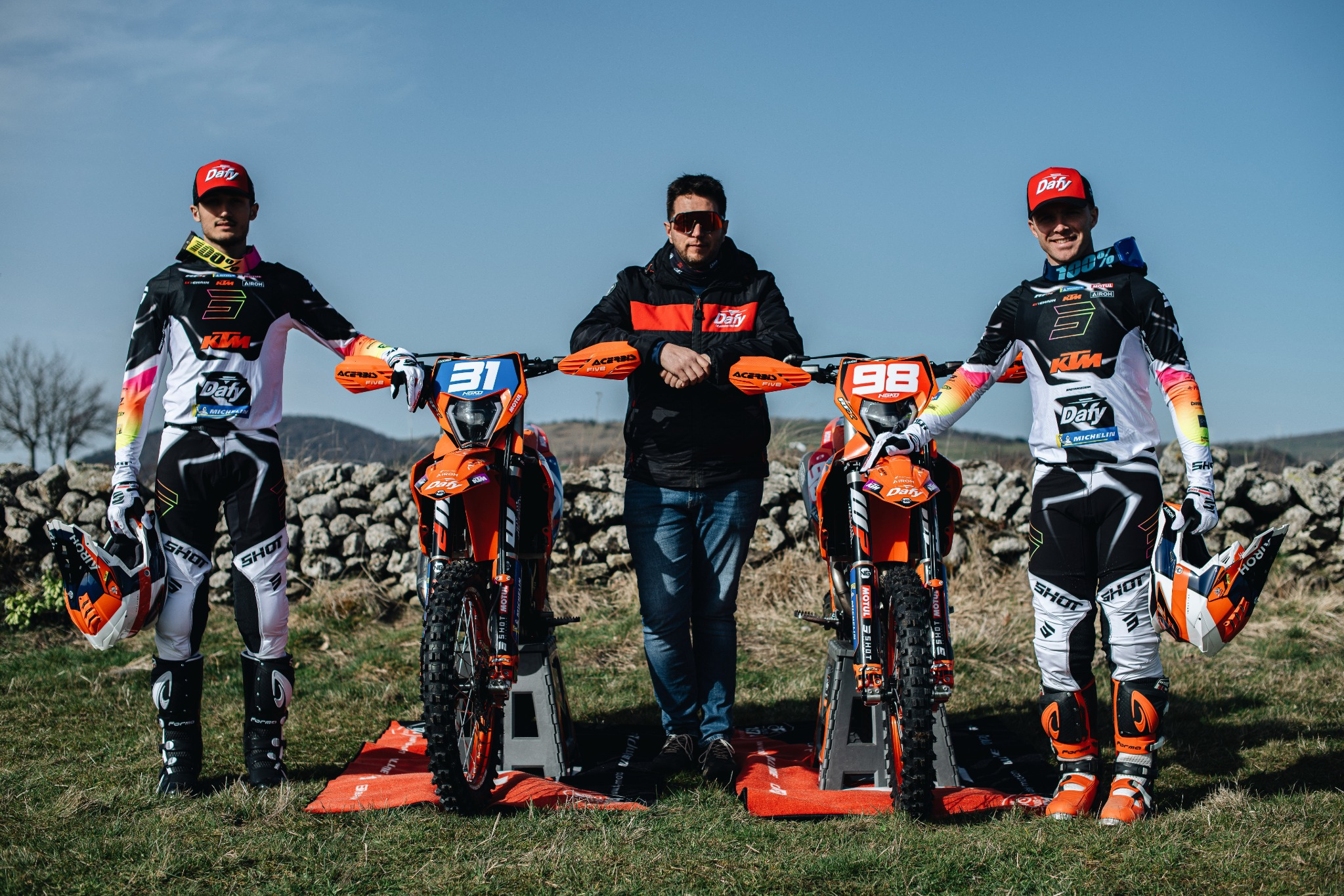 Pilotes du team Dafy Moto KTM posant avec leur manager et leurs motos d’enduro lors d’un shooting officiel.